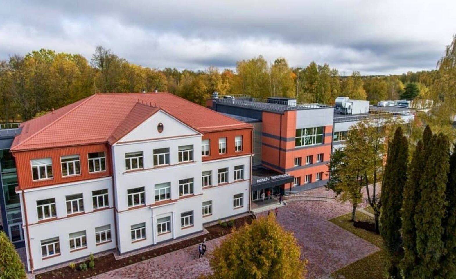 Ropažu vidusskolas ēka Ropažos. Balta trijstāvu ēka ar sarkanu dakstiņu jumtu un modernu, stiklotu piebūvi