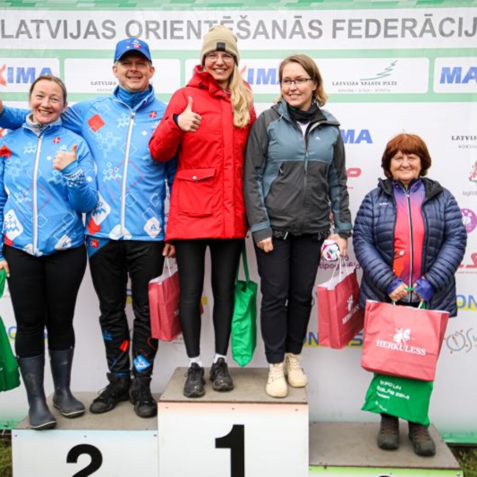 Orientēšanās sacensības - 5 skolotāji pie plakāta ar iegūtām balvām