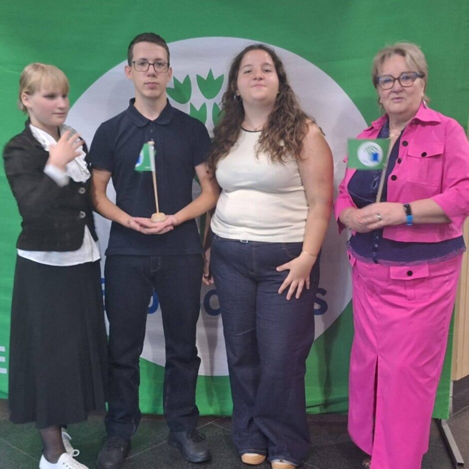 Skolotāja un 3 skolēni pie Ekoskolas Zaļā karoga