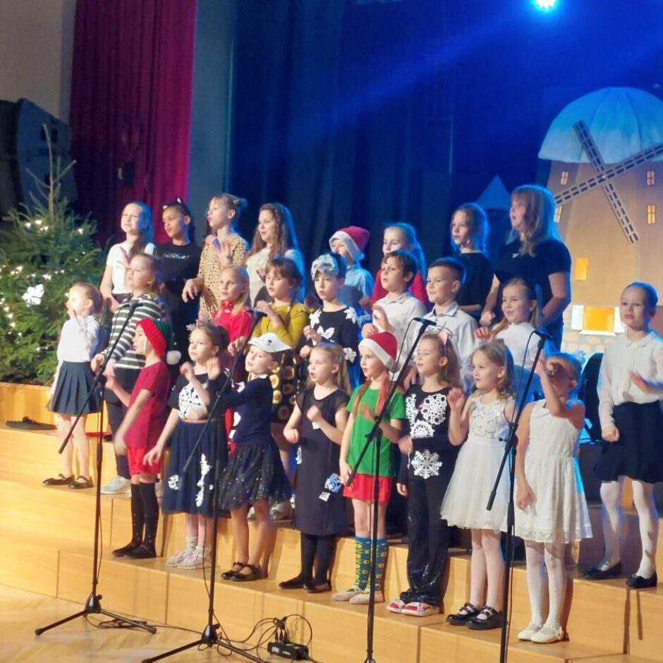 1.-4. klašu koris- skolēni ar rūķa cepurēm dzied