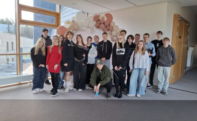 vidusskolēni pēc konferences - visi dalībnieki pie sienas ar baloniem