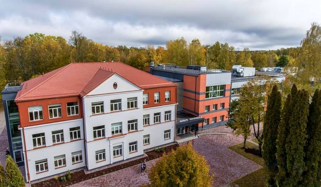 Ropažu vidusskolas ēka Ropažos. Balta trijstāvu ēka ar sarkanu dakstiņu jumtu un modernu, stiklotu piebūvi