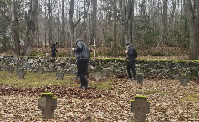 3 skolēni grābj rudens lapas Brāļu kapos
