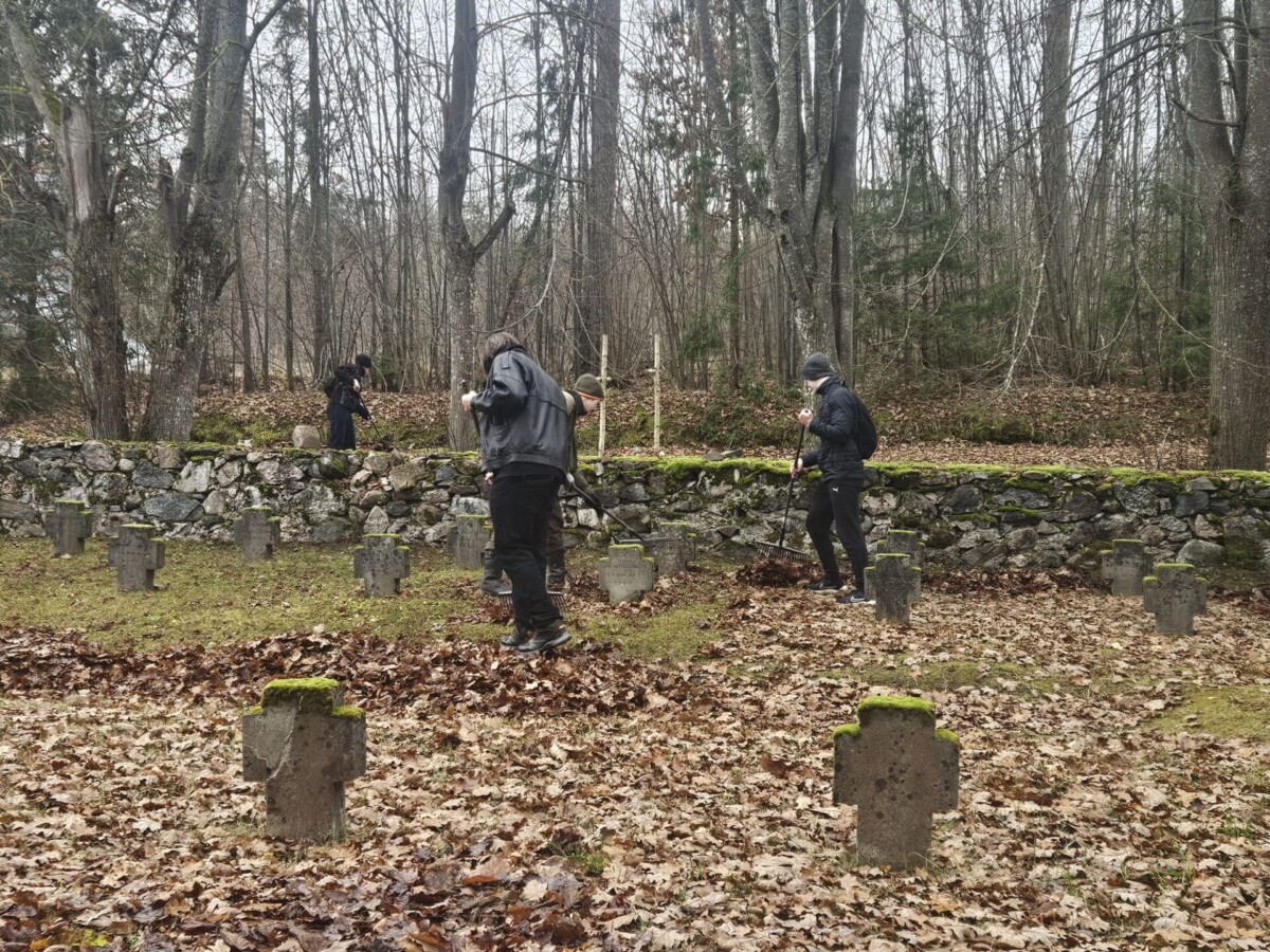 3 skolēni grābj rudens lapas Brāļu kapos